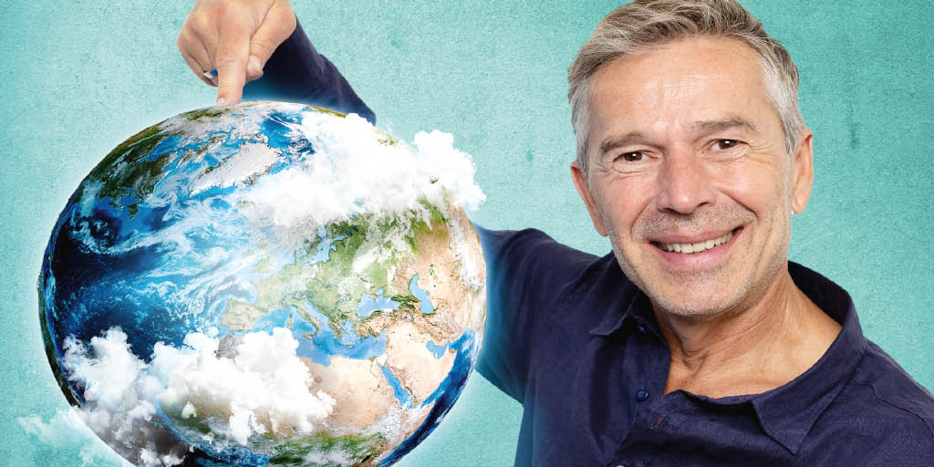 Ein lächelnder Mann zeigt mit dem Finger auf eine Erdkugel, die teilweise von weißen Wolken umgeben ist. Der Hintergrund ist türkisfarben.